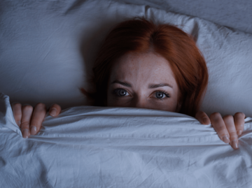 Frau ängstlich unter Bettdecke | © Getty Images/Axel Bueckert