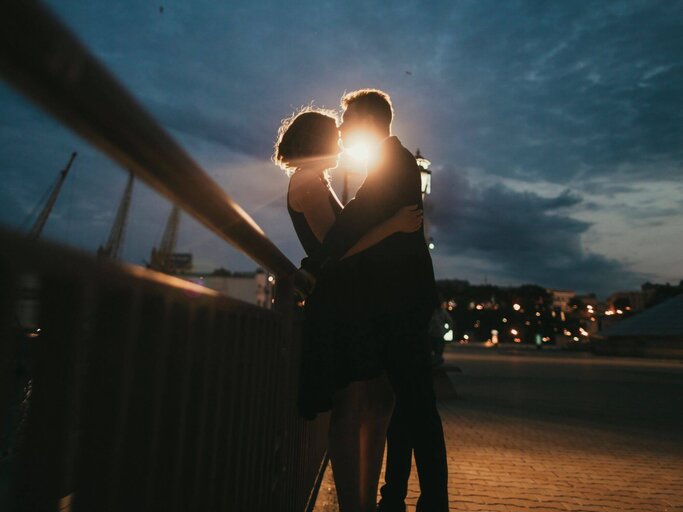 Mann und Frau küssen sich an Geländer | © Getty Images/Kateryna Soroka
