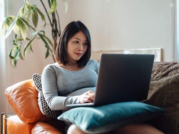 Frau am Laptop auf der Couch | © Getty Images/Oscar Wong