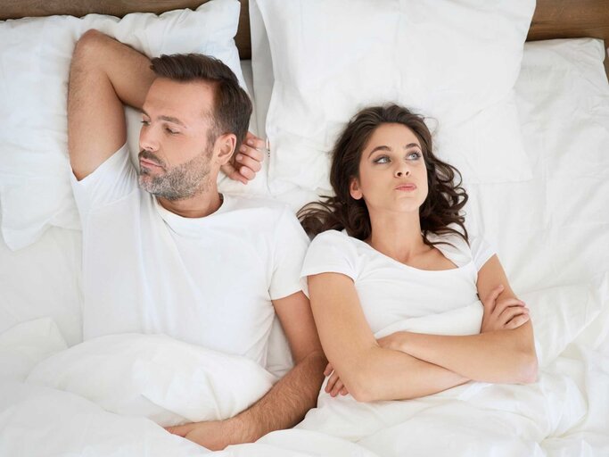 Paar liegt zusammen im Bett und schaut sich nicht an  | © Getty Images/Westend61
