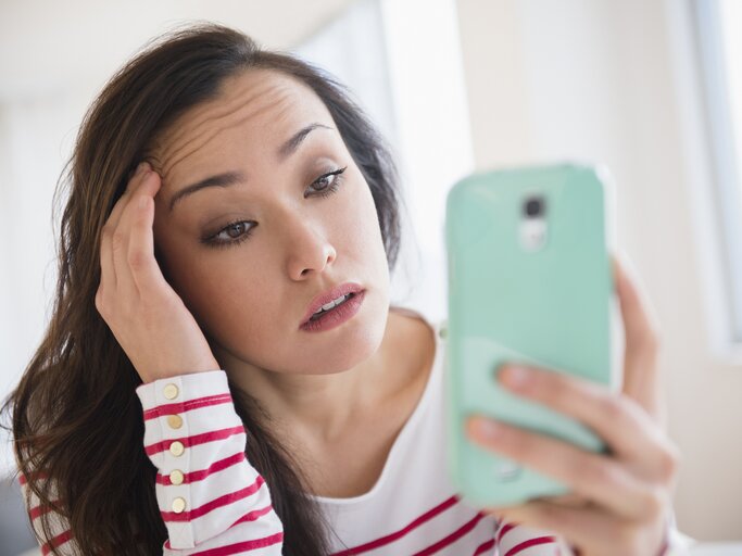 Frau schaut frustriert auf ihr Handy | © Getty Images/JGI/Jamie Grill