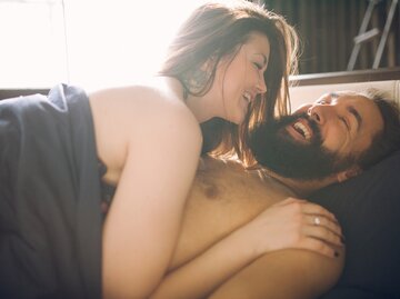 Junges Paar liegt halbnackt im Bett und lacht | © Getty Images/Sophie Garaeva / EyeEm