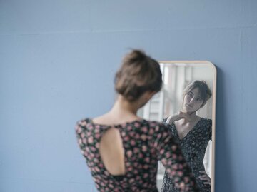 Frau betrachtet sich im Spiegel | © Getty Images/Westend61