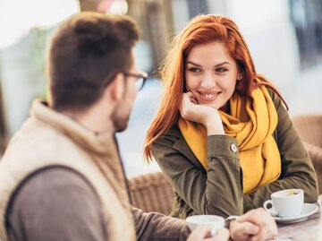 Frau lächelt man beim Kaffeetrinken an | © Getty Images/Jovanmandic