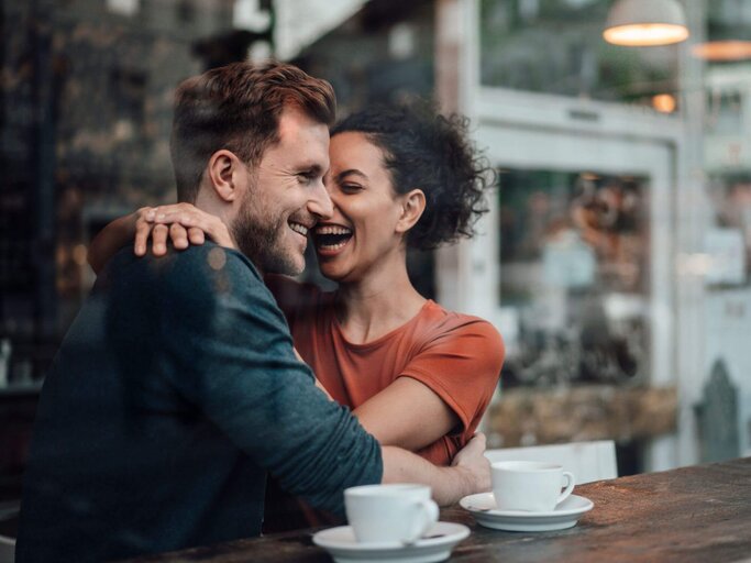 Frau und Mann umarmen sich im Café | © Getty Images/Westend61
