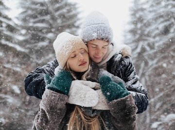 Junges Paar umarmt sich im Schnee | © Getty Images/Halfpoint Images