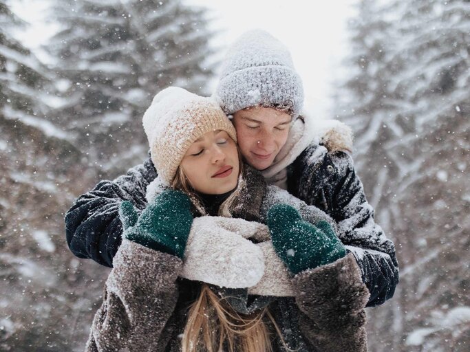Junges Paar umarmt sich im Schnee | © Getty Images/Halfpoint Images