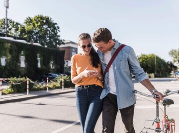 Mann und Frau gehen Straße entlang und lachen | © Getty Images/Westend61