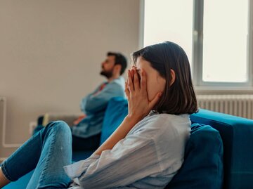 Verzweifelte Frau neben Mann auf Couch | © Getty Images/PixelsEffect