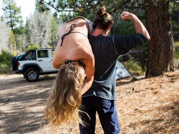 Muskulöser Mann hat sich eine blonde Frau über die Schulter geworfen. | © Getty Images/Jamie Kingham