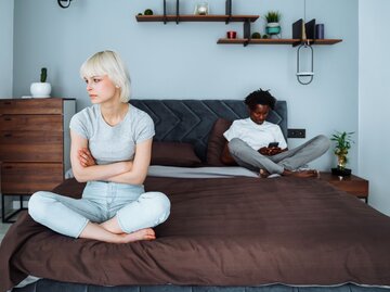 Ein Paar sitzt distanziert auf einem Bett und schweigt sich an | © Getty Images / Olga Rolenko