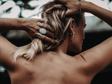 Rückenansicht einer Frau, die sich die Haare hochhält | © Getty Images/Kseniia Kapris / EyeEm