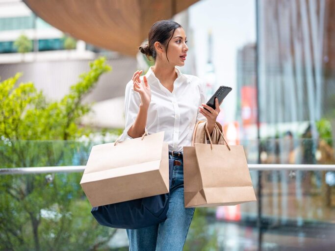 Frau mit Shoppingtüten und Handy | © Getty Images/Jackyenjoyphotography