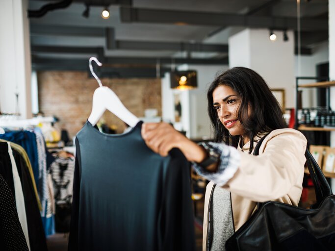Frau schaut sich beim Shoppen eine Bluse an | © Getty Images/Tom Werner