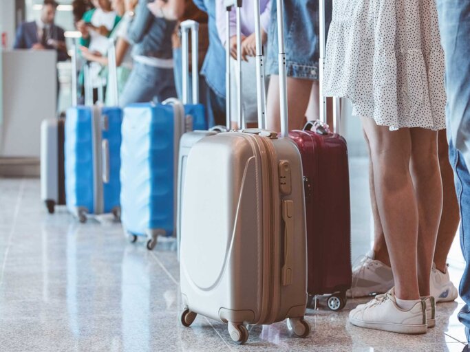 Passagiere mit Gepäck warten am Flughafen in der Schlange | © Getty Images/izusek