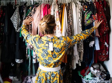 Frau sucht Klamotten in Kleiderschrank | © Getty Images/Westend61