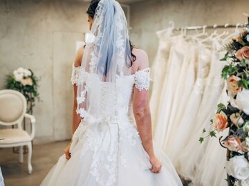 Frau trägt Brautkleid im Brautmodengeschäft | © Getty Images/South_agency