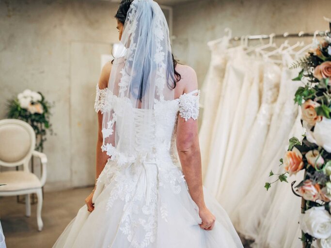 Frau trägt Brautkleid im Brautmodengeschäft | © Getty Images/South_agency
