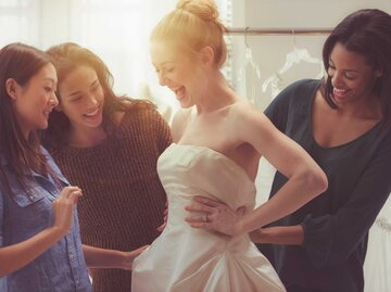 Frau probiert mit Freundinnen Brautkleid an | © Getty Images/Jose Luis Pelaez Inc