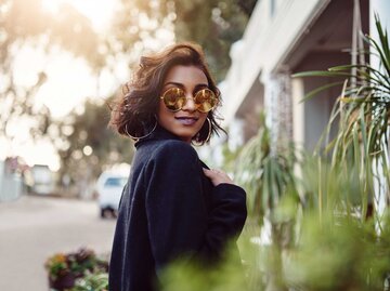 Kleine Frau mit Sonnenbrille lächelt in die Kamera | © Getty Images/Adene Sanchez