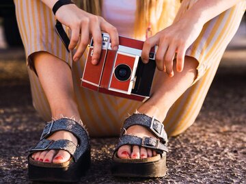 Person mit Sandalen und alter Kamera | © Getty Images/Westend61