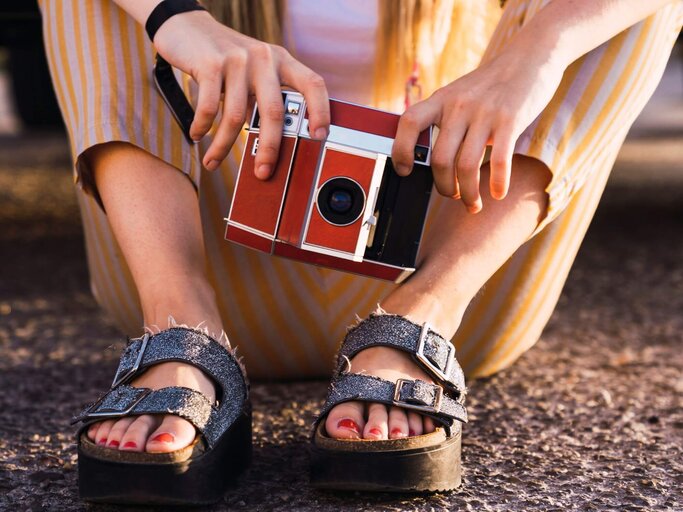 Person mit Sandalen und alter Kamera | © Getty Images/Westend61