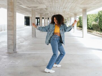 Junge Frau tanzt in Jeans unter einer Autobahnbrücke | © Getty Images/Westend61
