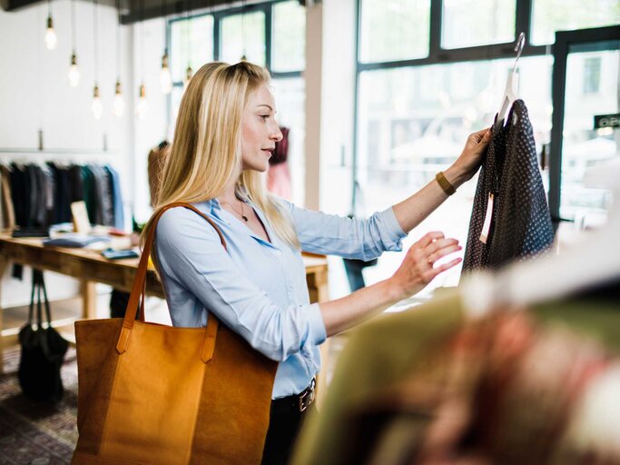 Frau schaut sich beim Shoppen ein Kleidungsstück an | © Getty Images/Tom Werner