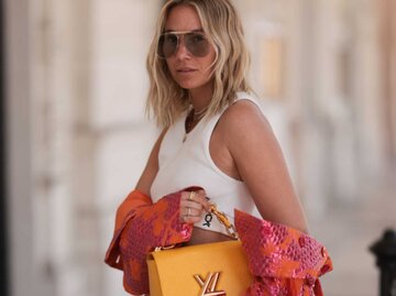 Frau trägt rosa-orangefarbene Jacke, Midirock, weißes, BH-Oberteil und gelbe Ledertasche  | © Getty Images/Jeremy Moeller / Kontributor
