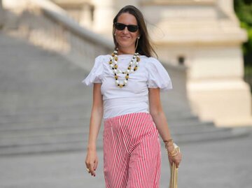 Alba Garavito Torre trägt rot-weiß gestreifte Leinenhose, und weißes Top mit Statementschmuck | © Getty Images/Edward Berthelot / Kontributor