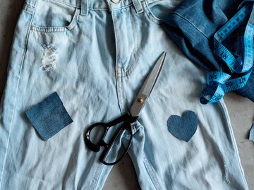 Jeans, Schere, Patches und Messband auf einem Bild | © Getty Images/Yuliia Kokosha