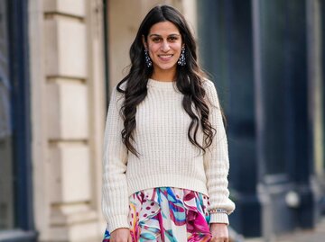 Brünette Frau trägt florales Maxikleid mit einem cremefarbenen Pullover  | © Getty Images/Edward Berthelot