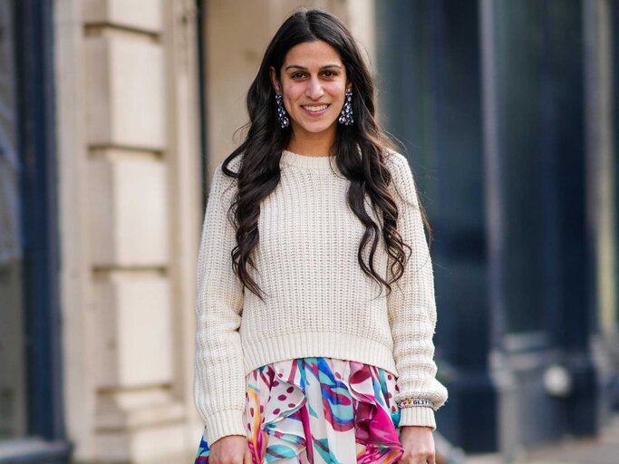 Brünette Frau trägt florales Maxikleid mit einem cremefarbenen Pullover  | © Getty Images/Edward Berthelot