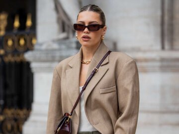 Caroline Ebo trägt einen beigen Blazer, eine bordeauxrote Jacquemus-Tasche und eine olivgrüne Hose mit Seitentaschen | © Getty Images/Christian Vierig