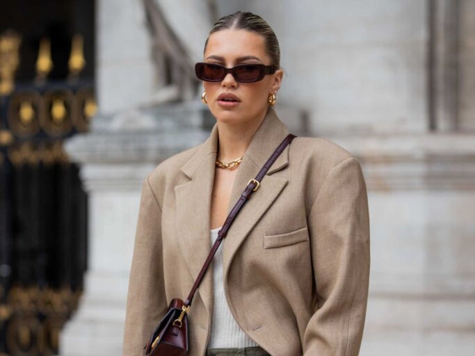 Caroline Ebo trägt einen beigen Blazer, eine bordeauxrote Jacquemus-Tasche und eine olivgrüne Hose mit Seitentaschen | © Getty Images/Christian Vierig