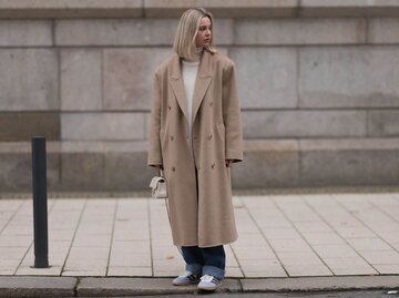 Person in Mantel und Sneaker an Straße | © Getty Images/Jeremy Moeller