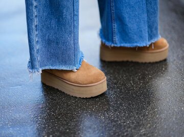 Close-up von braunen UGGs und blauen Jeans | © Getty Images/Edward Berthelot