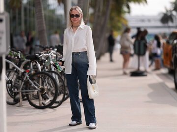 Streetstyle einer blonden Frau, sie trägt Blue Jeans und hat eine weiße Bluse vorne in den Hosenbund gesteckt. | © Getty Images/Jeremy Moeller