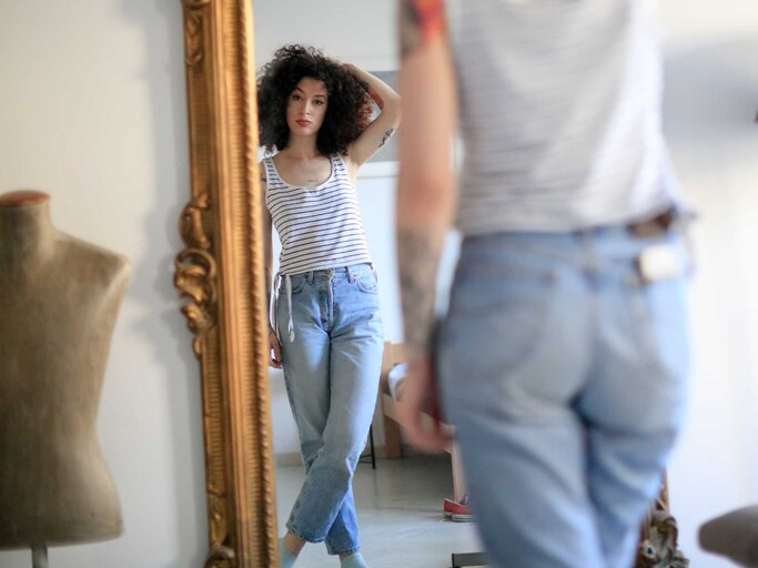 Frau vor dem Spiegel in Jeans | © Getty Images/zoranm