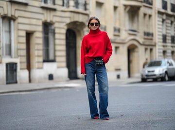 Streetstyle von Diane Batoukina in blauer Jeans und rotem Pullover | © Getty Images/Edward Berthelot