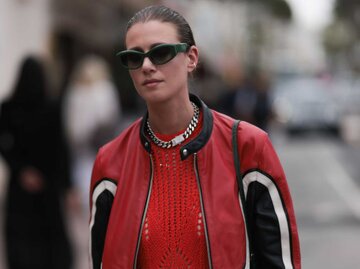 Frau trägt ein rotes Häkelkleid, eine schwarze Sonnenbrille und eine schwarz/weiß/rote Biker-Lederjacke | © Getty Images/Jeremy Moeller