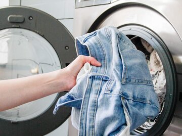 Jeans wird in Waschmaschine gelegt | © Getty Images/ Kinga Krzeminska