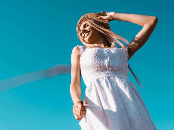 Frau in weißem Kleid und mit Strohhut | © Getty Images/LightFieldStudios