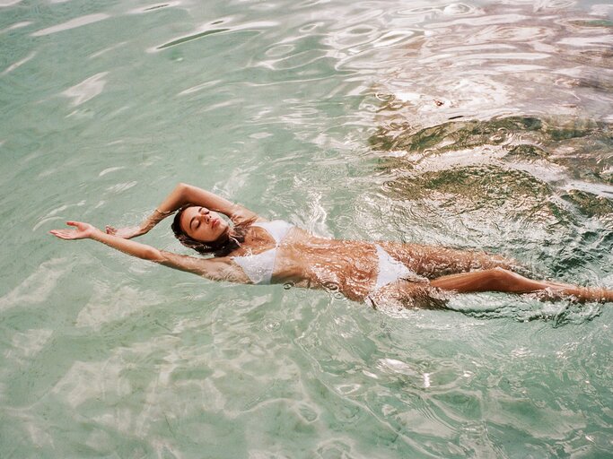 Frau liegt mit Bikini im Wasser | © Getty Images/Patrick Fraser