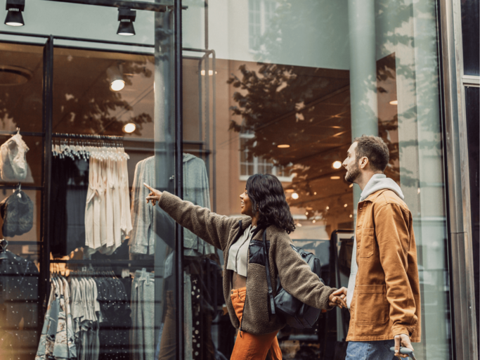 Frau und Mann beim Shoppen vor Schaufenster | © Getty Images/Johner Images