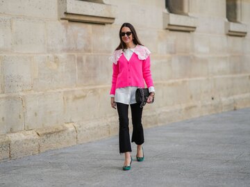 Frau trägt weiße Bluse, pinken Cardigan und schwarze Hose | © Getty Images/Edward Berthelot