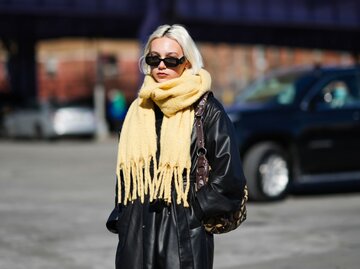 Junge Frau trägt Lederjacke und gelben Kuschelschal | © Getty Images/Edward Berthelot 