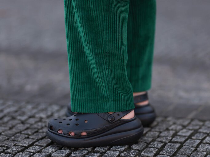 Frau trägt Schwarze Crocs und grüne Cordhose | © Getty Images/Jeremy Moeller 