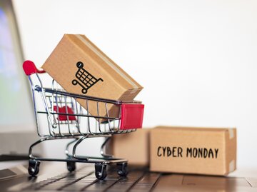 Bild von einem Paket in einem Einkaufswagen. Ein anderes Paket liegt auf dem Boden mit der Aufschrift "Cyber Monday" | © Getty Images/R Franca / EyeEm