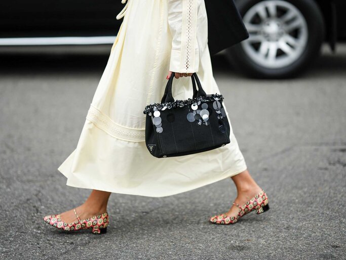 Streetstyle-Look mit bunten Ballerinas, einer Pailletten-Tasche und einem beigen Sommerkleid. | © Getty Images / Edward Berthelot 